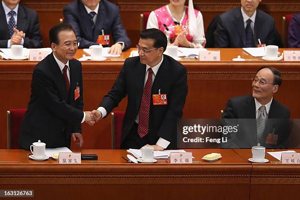 Chinese Premier Wen Jiabao shakes hands with Chinese Vice Premier Li Keqiang as Chinese Vice Premier Wang Qishan looks on after Wen delivered his...