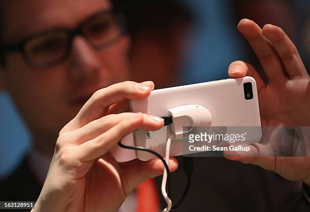 Stand host takes a picture with the Blackberry Z10 smartphone, which is the Germany version of the Blackberry 10, at the Vodafone stand at the 2013...