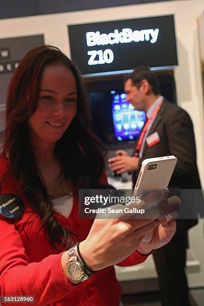 Stand hostess takes a picture with the Blackberry Z10 smartphone, which is the Germany version of the Blackberry 10, at the Vodafone stand at the...