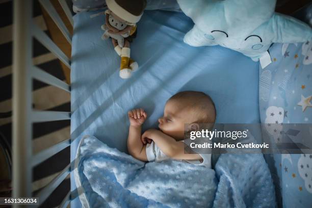 close up of adorable newborn child infant who is sleeping on his back. dreamtime. - cot stock pictures, royalty-free photos & images