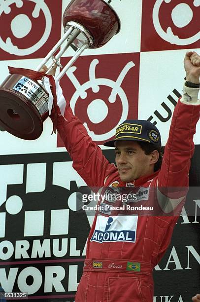 McLaren Ford driver Ayrton Senna of Brazil holds the trophy aloft after his victory in the Japanese Grand Prix at the Suzuka circuit in Japan. \...