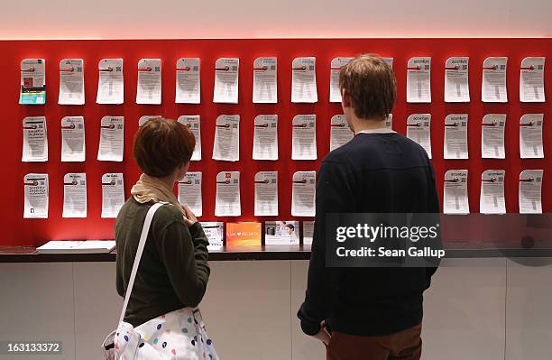 People look at pieces of paper with job openings from technoogy companies at the 2013 CeBIT technology trade fair on March 5, 2013 in Hanover,...