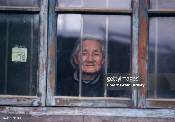 An elderly woman looks out of a window in Shaanxi province, China, 1997.