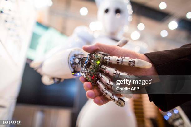 Visitor holds a hand of AILA, or Artificial Intelligence Lightweight Android, during a demonstration at the German Research Center for Artificial...