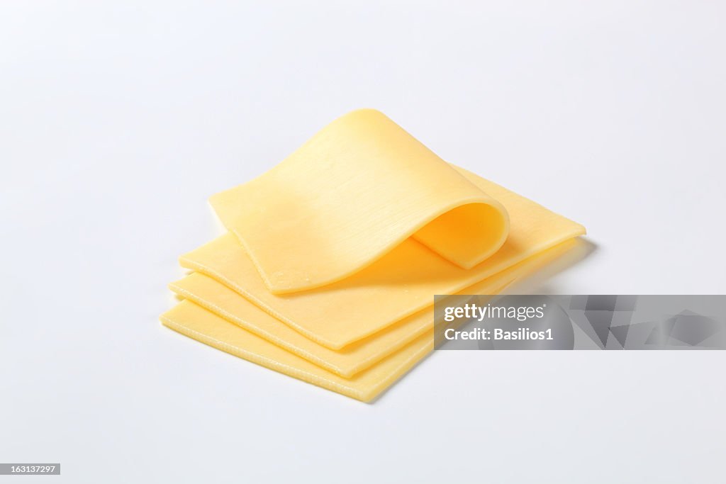 Four cut up slices of cheese isolated on a white background