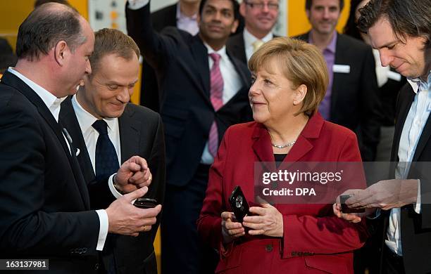 German Chancellor Angela Merkel holds a tapping proof BlackBerry mobile device at the stand of Secusmart as she tours with Polish Prime Minister...