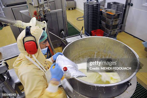 An employee of French ready made meals company "Delpeyrat Traiteur" sheds milk in a tank as he works on the preparation of hachis parmentier with...