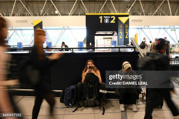 Passengers wait at Gatwick Airport, south of London, on August 29, 2023 after UK flights were delayed over a technical issue. Flights to and from the...