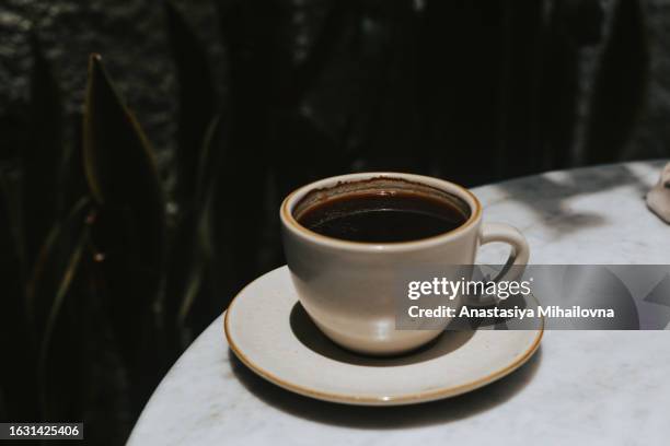 black coffee in a white mug on a round table - americano photos et images de collection