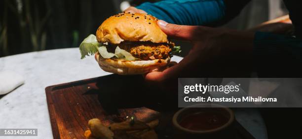 man holding vegan burger with bean patty and vegetables - vegetable kebab stock pictures, royalty-free photos & images