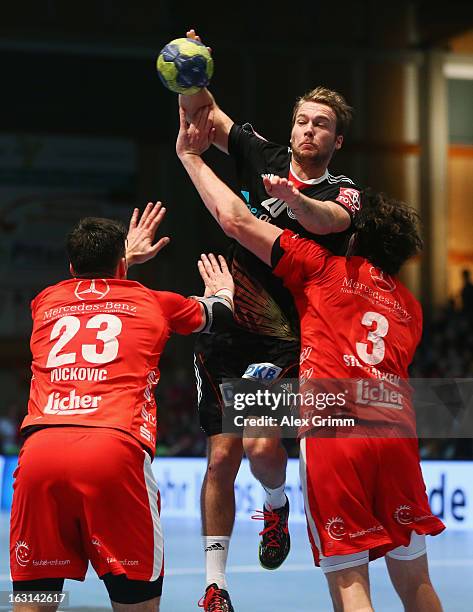 Kevin Schmidt of Germany is challenged by Nenad Vuckovic and Jonathan Stenbacken of Melsungen during a benefit match between the German national...