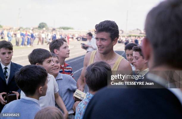 Michel Jazy. En France, Michel JAZY, athlète, coureur de demi-fond, portant un maillot jaune, entouré d'enfants après la course.