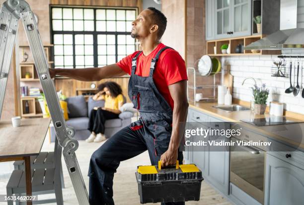 un riparatore che installa una scala a pioli in una cucina domestica - scala a pioli foto e immagini stock