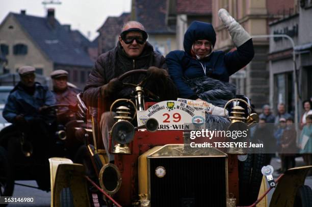 The Rally Of Old Cars Paris Vienna 1965. En Autriche, dans une rue, à l'avant d'un tacot,un homme avec des lunettes de pilote, conduisant et une...