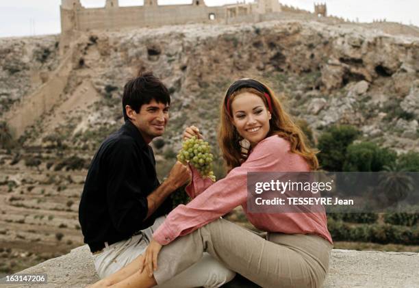 Shooting In Spain Of The Film 'L'Homme De Marrakech' By Jacques Deray. Dans un décor montagneux, assis sur une terrasse, Claudine AUGER, avec un...