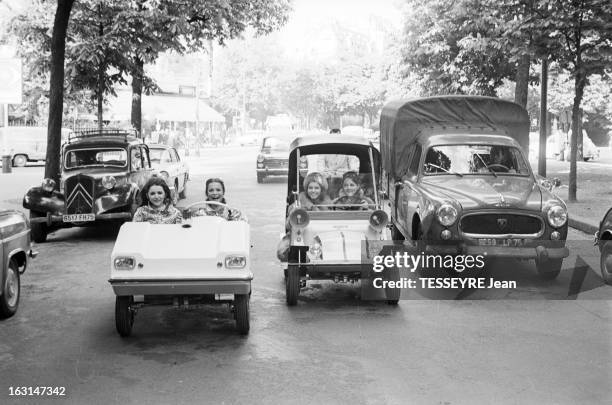 The Mini Cars Vogue In Paris. En France, sur une avenue bordée d'arbres, des jeunes femmes souriantes, roulant à bord de de modèles différent de...