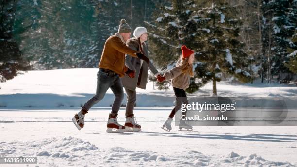 family enjoying ice skating - father and mother with their daughter playing in the snow stock pictures, royalty-free photos & images