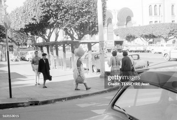 Algiers In 1962. En juin 1962, une femme algérienne voilée transportant un gros paquet sur sa tête, marche sur un trottoir de la rue d'Isly, la...
