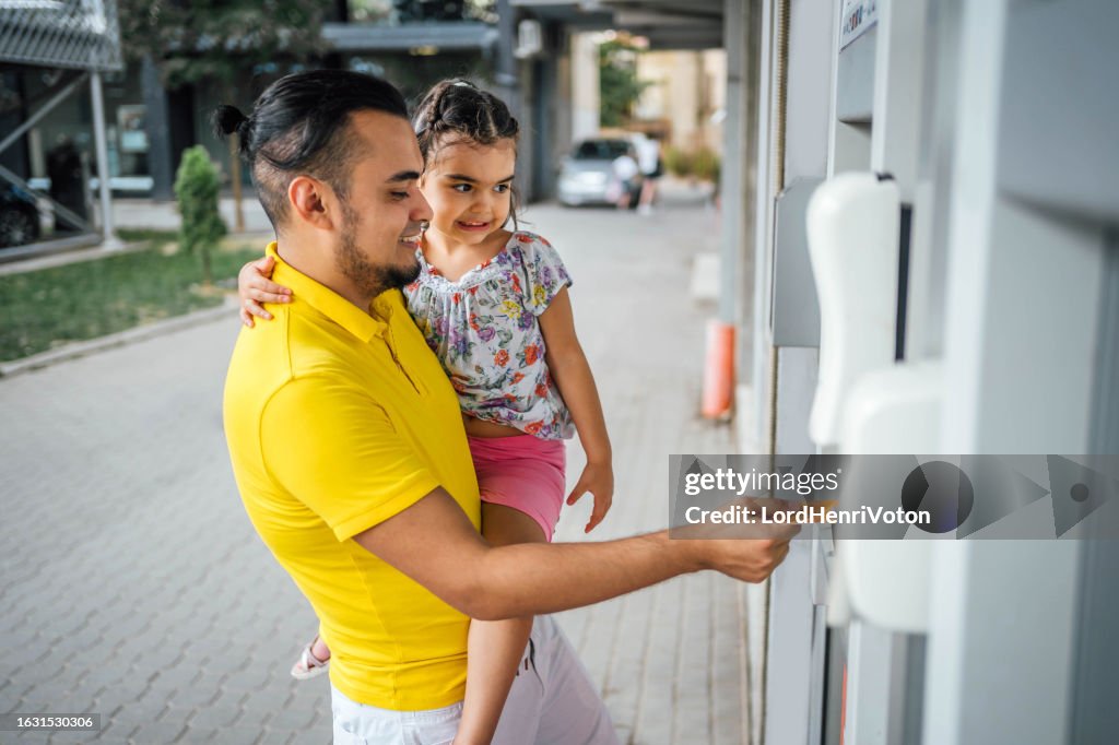 Father and daughter withdrawing money from an ATM