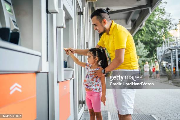 father and daughter withdrawing money form cash machine - man atm smile stock pictures, royalty-free photos & images