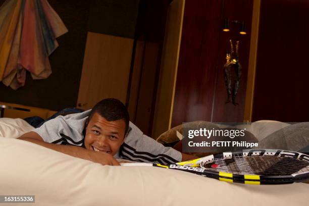 Rendezvous With Jo-Wilfried Tsonga. Attitude souriante de Jo-Wilfried TSONGA en jeans et tee-shirt Adidas, allongé sur le ventre sur le lit d'une...