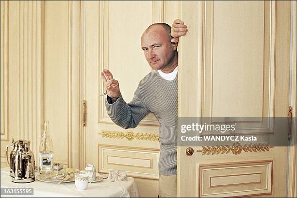 Phil Collins In Paris. Phil COLLINS posant par la porte entrebaillée de sa chambre au Plaza Athénée à Paris, soulevant une petite cuillère de la...