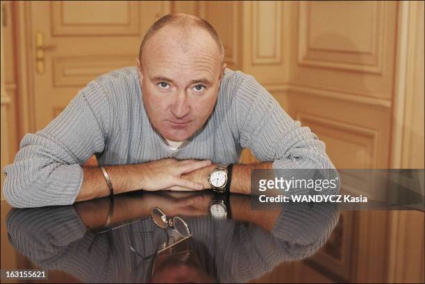 Phil Collins In Paris. Phil COLLINS posant assis dans une chambre du Plaza Athénée à Paris, les coudes sur la table..