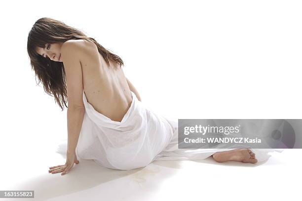 Rendezvous With Romance Bohringer. Photo studio : attitude sensuelle de Romane BOHRINGER assise par terre, nue, le corps enveloppé dans un drap blanc...