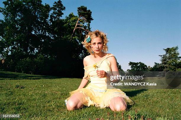 Julie Depardieu In The In Bois De Boulogne. Attitude de Julie DEPARDIEU en robe jaune, une fleur à la main, agenouillée sur l'herbe, près du Chalet...