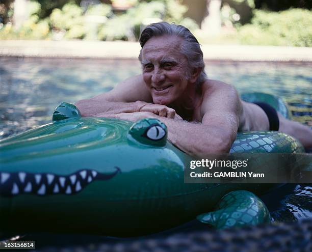 Kirk Douglas At Home In Beverly Hills. En Aout 1990, l'acteur américain,Kirk DOUGLAS en maillot de bain, sur un crocodile en plastique, chez lui, aux...