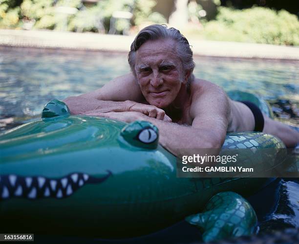 Kirk Douglas At Home In Beverly Hills. En Aout 1990, l'acteur américain,Kirk DOUGLAS en maillot de bain, sur un crocodile en plastique, chez lui, aux...