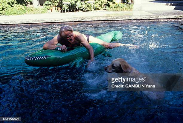 Kirk Douglas At Home In Beverly Hills. En Aout 1990, l'acteur américain,Kirk DOUGLAS en maillot de bain, sur un crocodile en plastique, chez lui, aux...