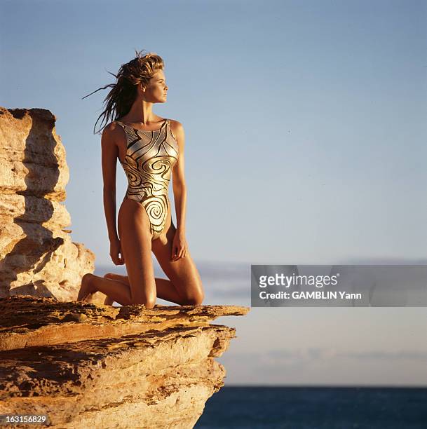 Photo Session With Elle Mac Pherson. Août 1991, séance photo de la mannequin Elle MACPHERSON, en maillot de bain une pièce, agenouillée sur un rocher.