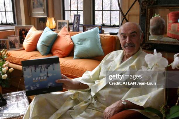 Rendezvous With Sean Connery In New York. Sean CONNERY en kimono blanc, montrant un livre sur la Chine, assis dans le salon de son appartement cosy...