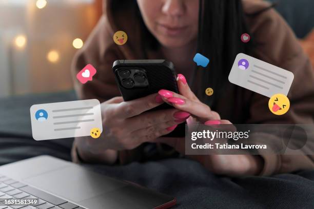 young attractive millennial generation woman cheerfully smiling while communicating with her friends and colleagues via smartphone and laptop. lifestyle photo with emoji - flirter photos et images de collection