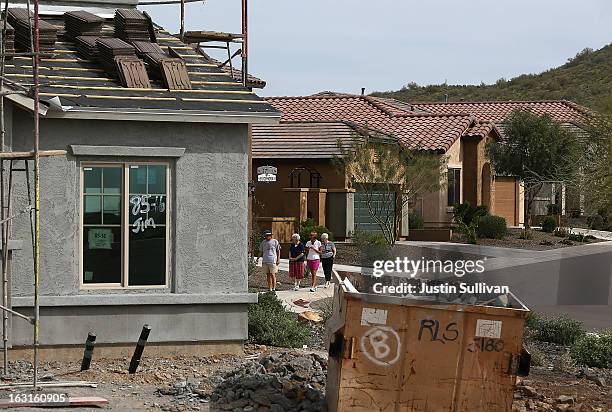 People walk by a home under construction at the Pulte Homes Fireside at Norterra-Skyline housing development on March 5, 2013 in Phoenix, Arizona. In...