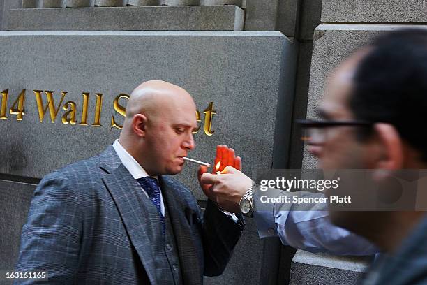 Man lights his cigaretta along Wall Street near the New York Stock Exchange on March 5, 2013 in New York City. The Dow Jones industrial average...