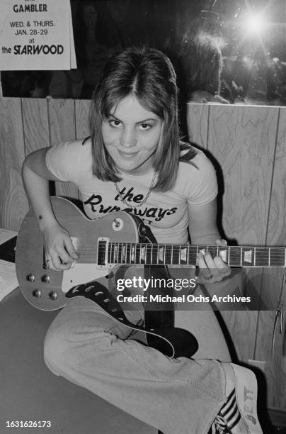 American singer, songwriter and guitarist Joan Jett playing a Gibson Les Paul guitar, wearing a t-shirt bearing the logo of her band The Runaways,...