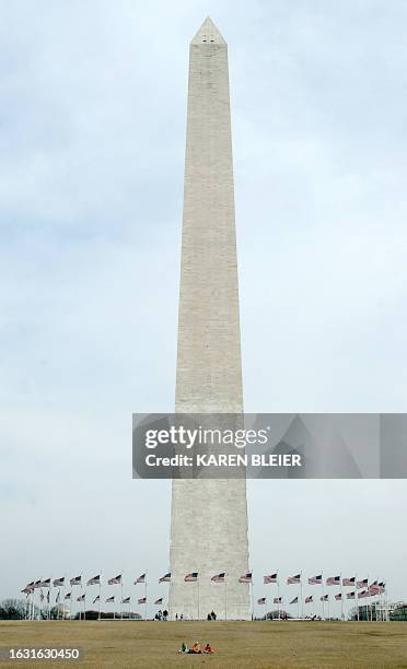 Visitors to the Washington Monument take a break 09 March on the National Mall in Washington, DC. The DC area is experiencing springlike temperatures...