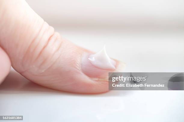 white moisturizing cream on nail. nail care concept. - peeling off stock pictures, royalty-free photos & images