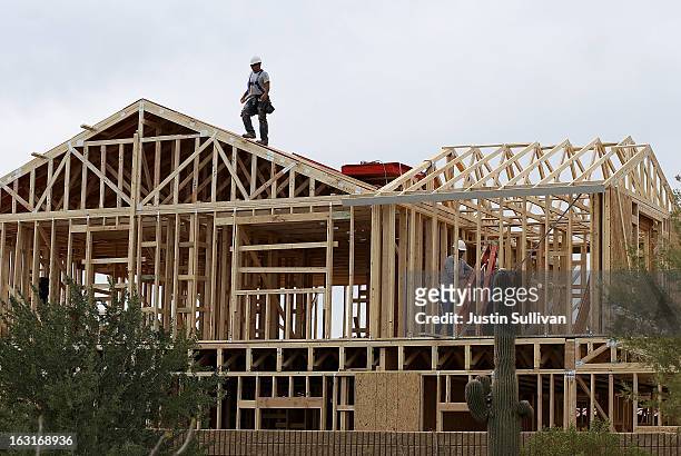 Worker climbs on the roof of a home under construction at the Pulte Homes Fireside at Norterra-Skyline housing development on March 5, 2013 in...