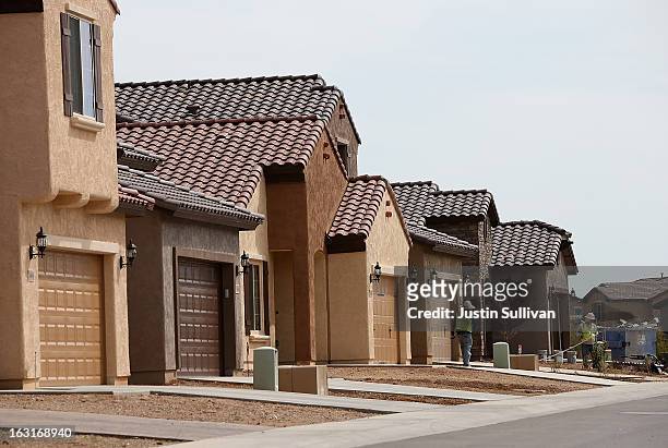 Workers stand in front of a row of new homes at the Pulte Homes Fireside at Norterra-Skyline housing development on March 5, 2013 in Phoenix,...