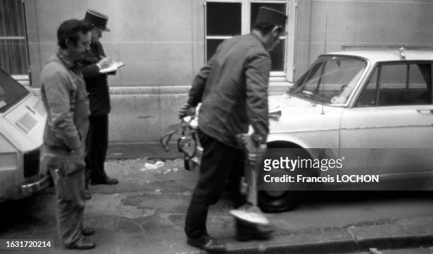 Un policier pose un sabot de Denver sur une roue de voiture en novembre 1975 à Paris.