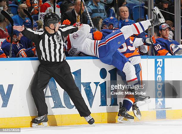 Casey Cizikas of the New York Islanders checks Alex Galchenyuk of the Montreal Canadiens into the bench at Nassau Veterans Memorial Coliseum on March...
