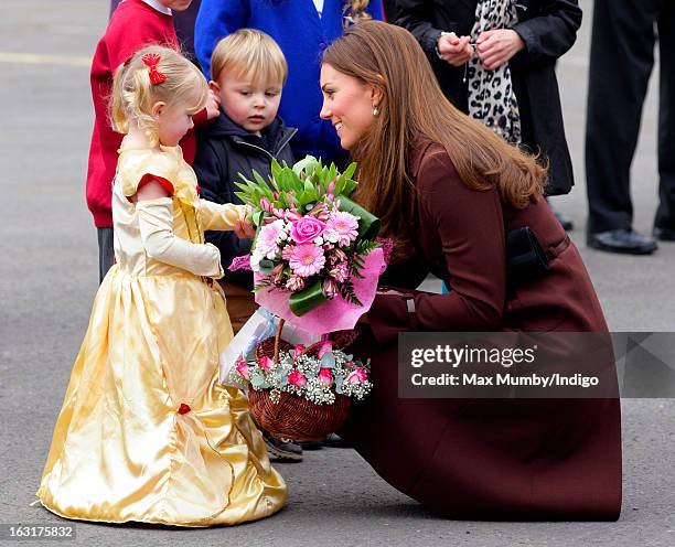 Catherine, Duchess of Cambridge receives a posy of flowers from a girl dressed as a princess as she visits Peaks Lane Fire Station whilst carrying...