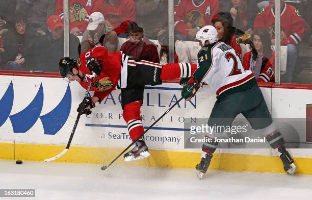 Kyle Brodziak of the Minnesota Wild hits Patrick Sharp of the Chicago Blackhawks forcing him off of his feet at the United Center on March 5, 2013 in...