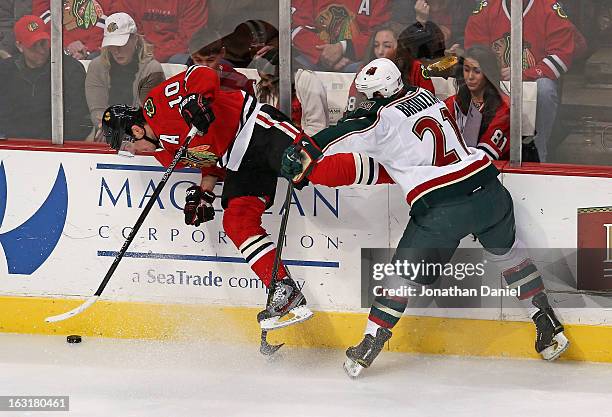 Kyle Brodziak of the Minnesota Wild hits Patrick Sharp of the Chicago Blackhawks forcing him off of his feet at the United Center on March 5, 2013 in...