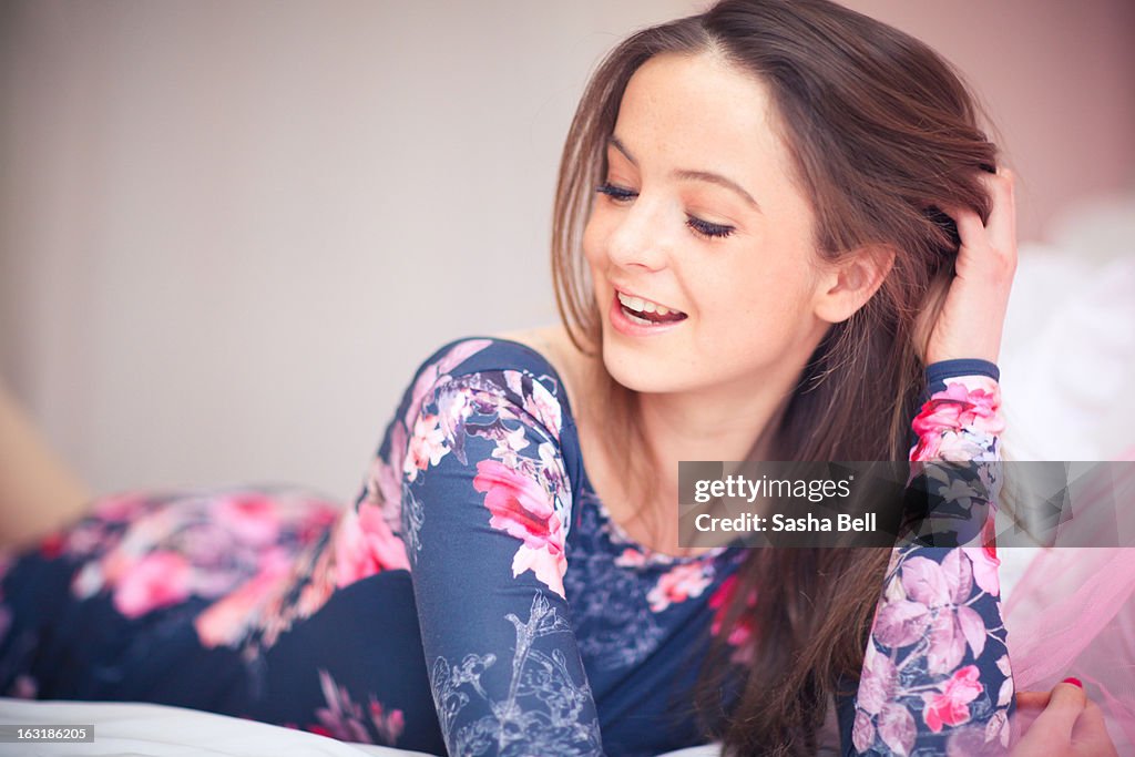 Girl Lying on Bed Laughing Wearing Floral Dress