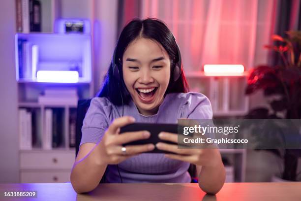 young woman use smartphone to playing online game in neon lights room - pre game stockfoto's en -beelden