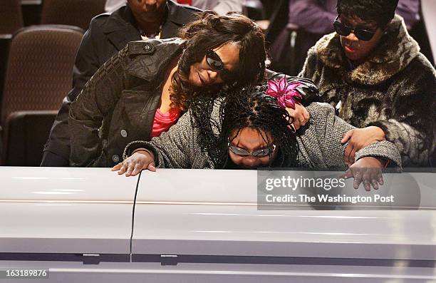 Tiffanee Price, left, mourns with Teresa Myles-Price, center, and Barbara Cromer, right, at a memorial service for Darrell Price Jr. And his...